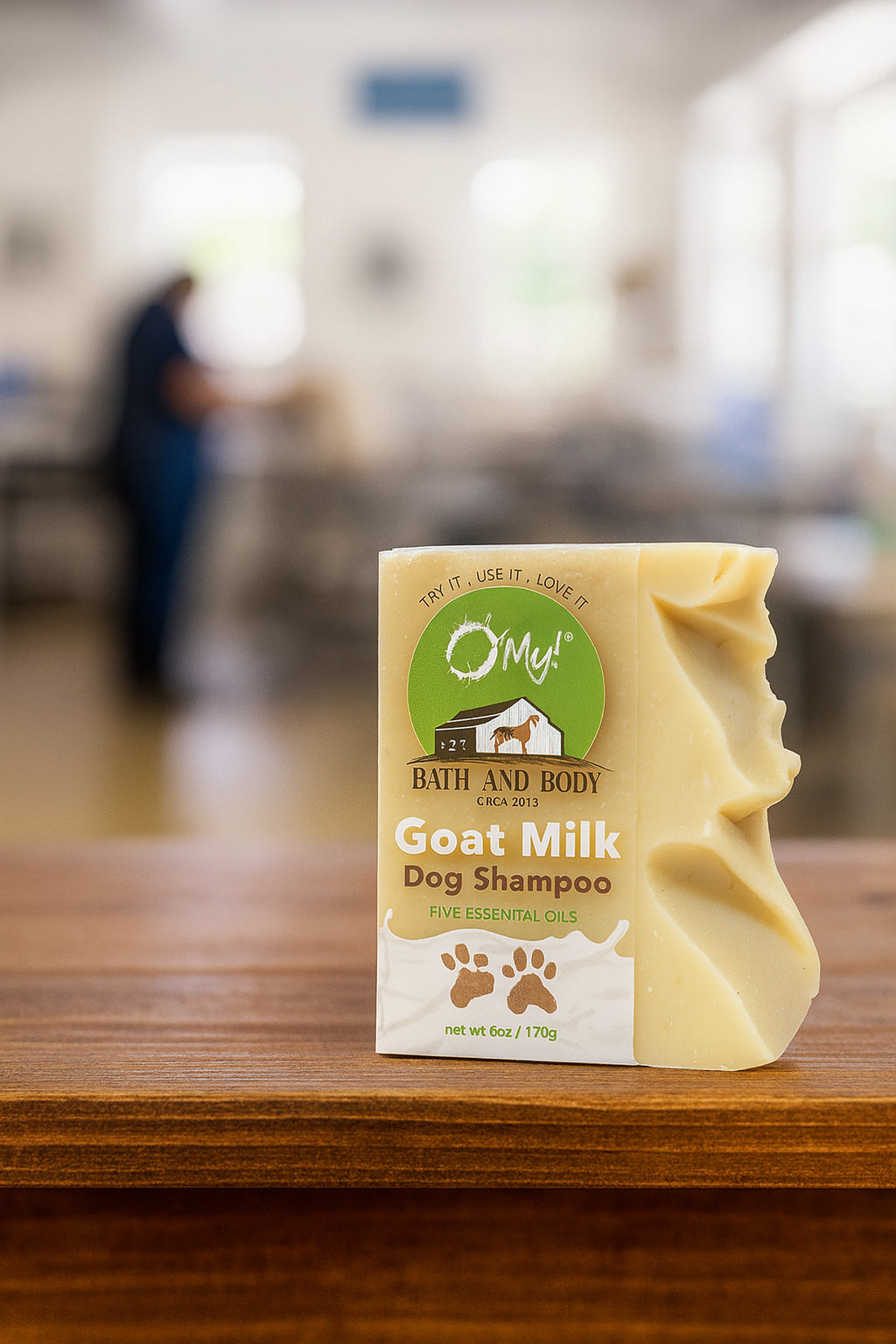 Bar of O'My Goat Milk Dog Shampoo soap on a wooden surface at a dog groomer.