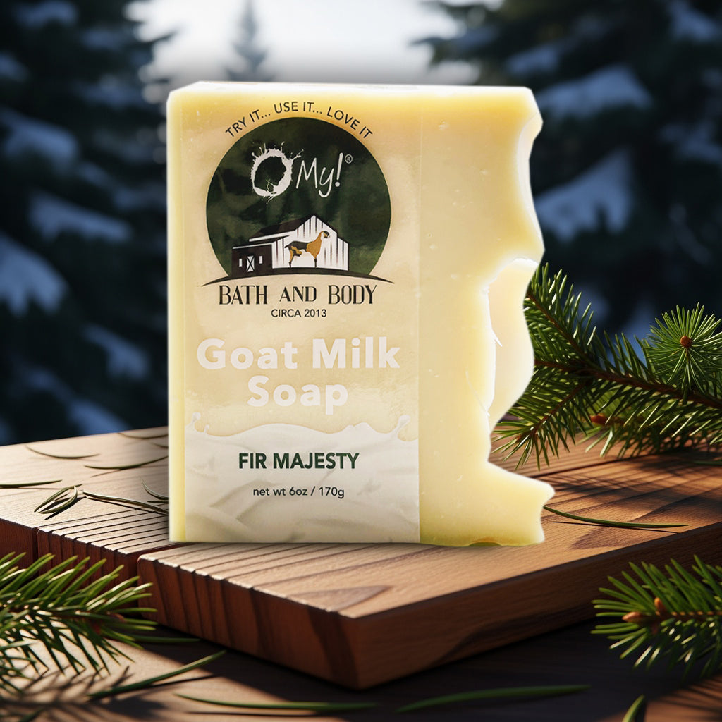 Bar of O My! goat milk soap labeled 'Fir Majesty' on a wooden surface with evergreen branches.