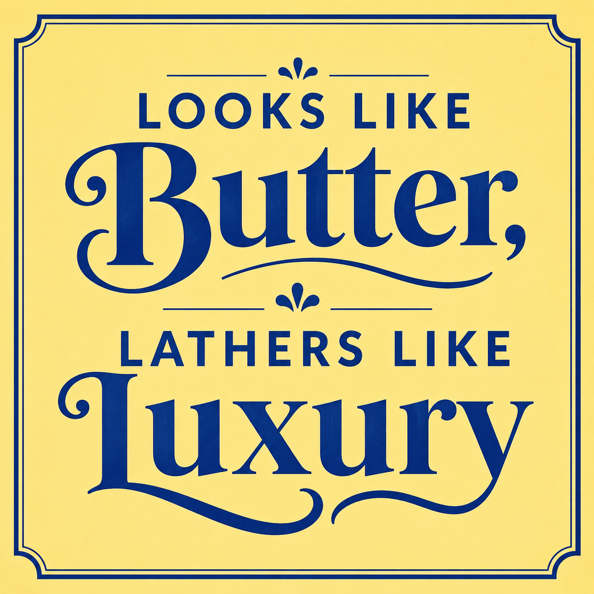 A square graphic with a pale yellow background and dark blue decorative text reading “Looks Like Butter, Lathers Like Luxury.” The design uses ornate serif lettering and a thin blue border.