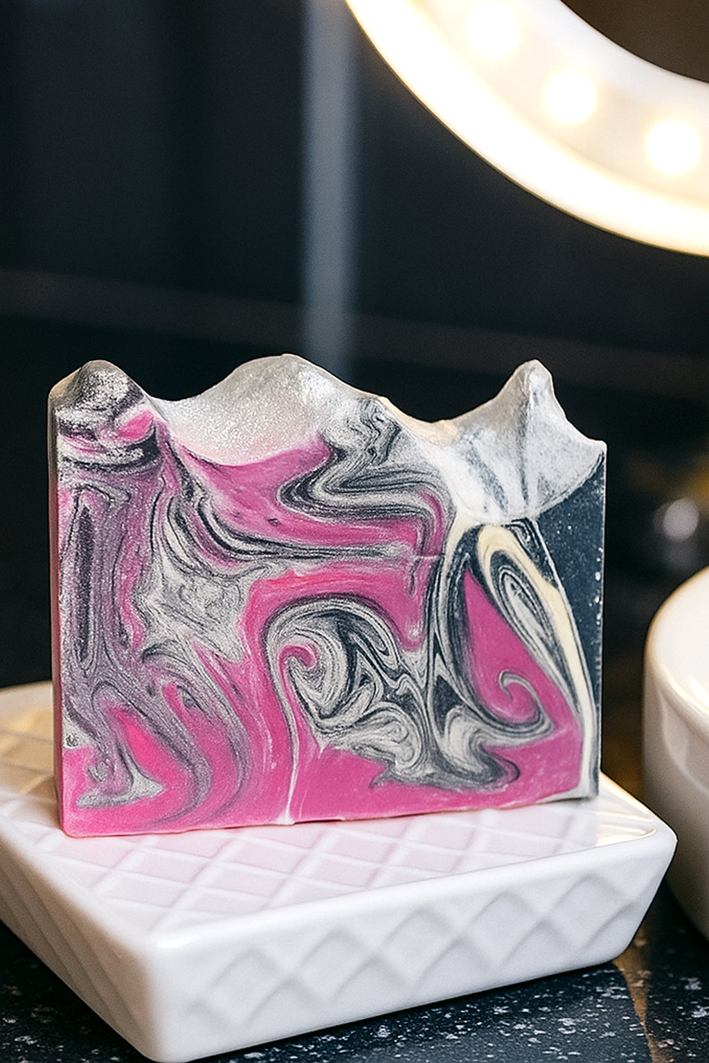 O My! Bath and Body Goat Milk Soap Artisan Black Raspberry Vanilla with eco glitter sitting on a porcelain soap tray to let the soap dry in open spaces