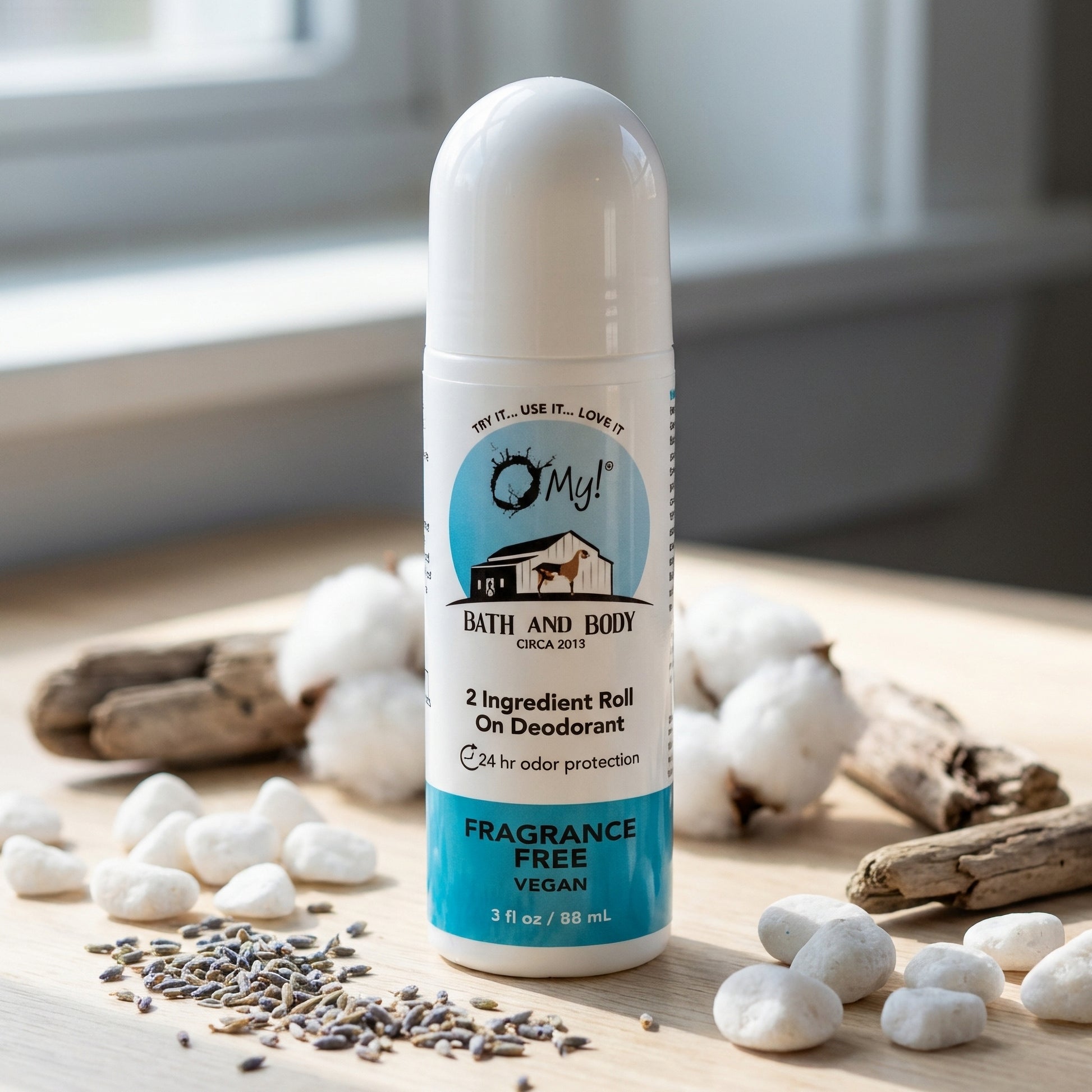 O My! Roll-on 2 ingredient deodorant on a wooden surface with cotton and lavender seeds.