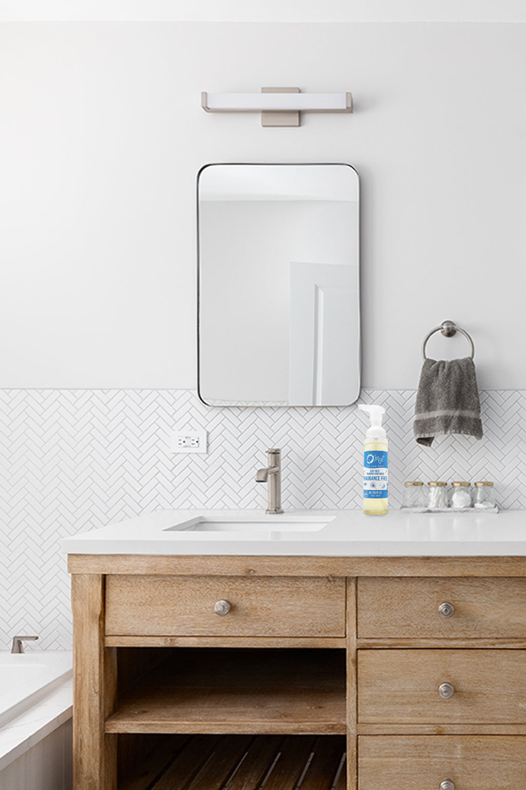 Bathroom vanity with wooden cabinets, mirror, and toiletries.  O My! Goat Milk Foaming Hand Wash is sitting by the sink.