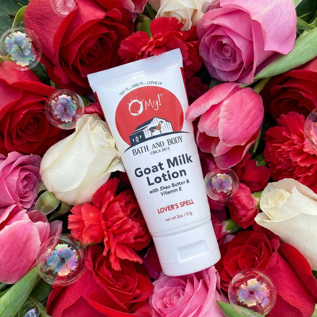 Tube of O My! Bath and Body Goat Milk Lovers Spell Lotion surrounded by red, pink, and white flowers.