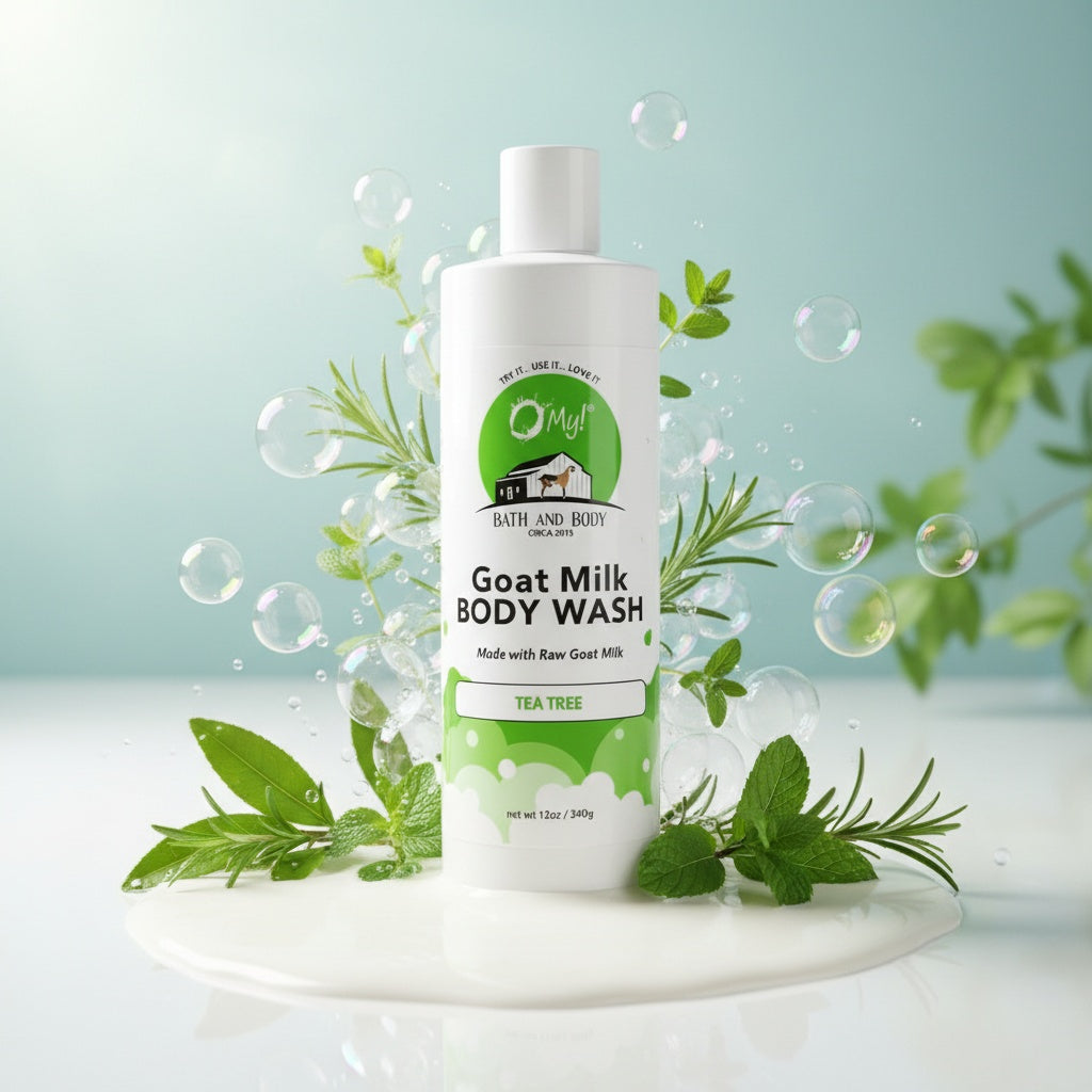 O My! Goat Milk Body Wash Tea Tree bottle surrounded by green leaves and bubbles on a milky background.